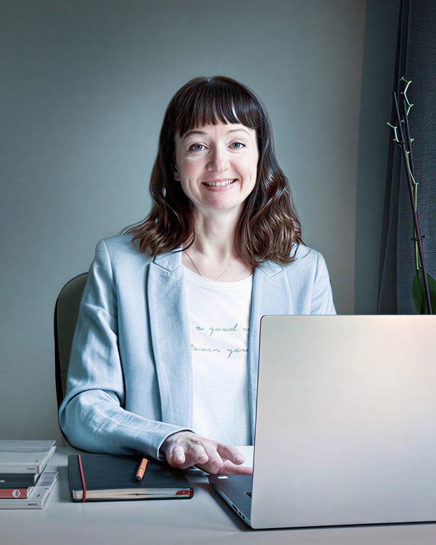 Olga Startceva smiling at her desk with a laptop